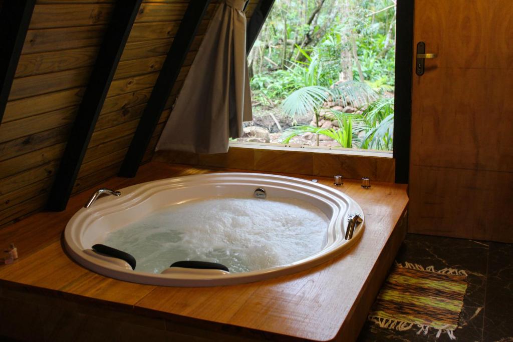 eine große Badewanne in einem Zimmer mit Fenster in der Unterkunft Chalé Suiço com Hidromassagem e café da Manhã in Praia Grande