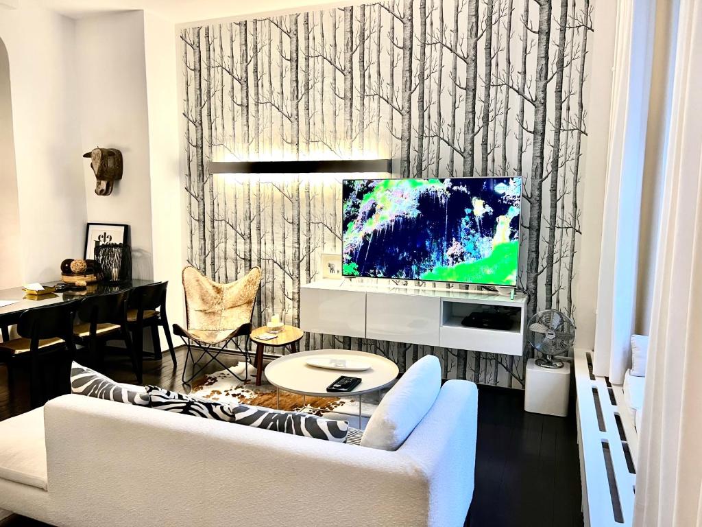 ein Wohnzimmer mit einem weißen Sofa und einem TV in der Unterkunft Cocoma-Design-Apartment Deluxe - very central in München