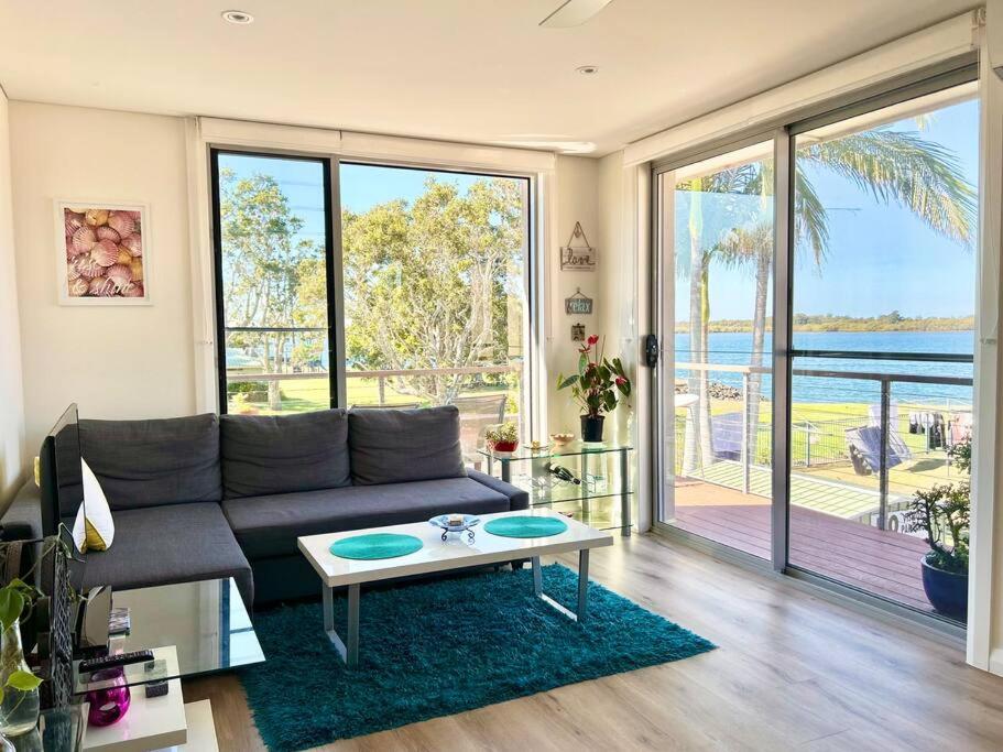 a living room with a couch and a table at Cosy unit with park & water view in Ballina