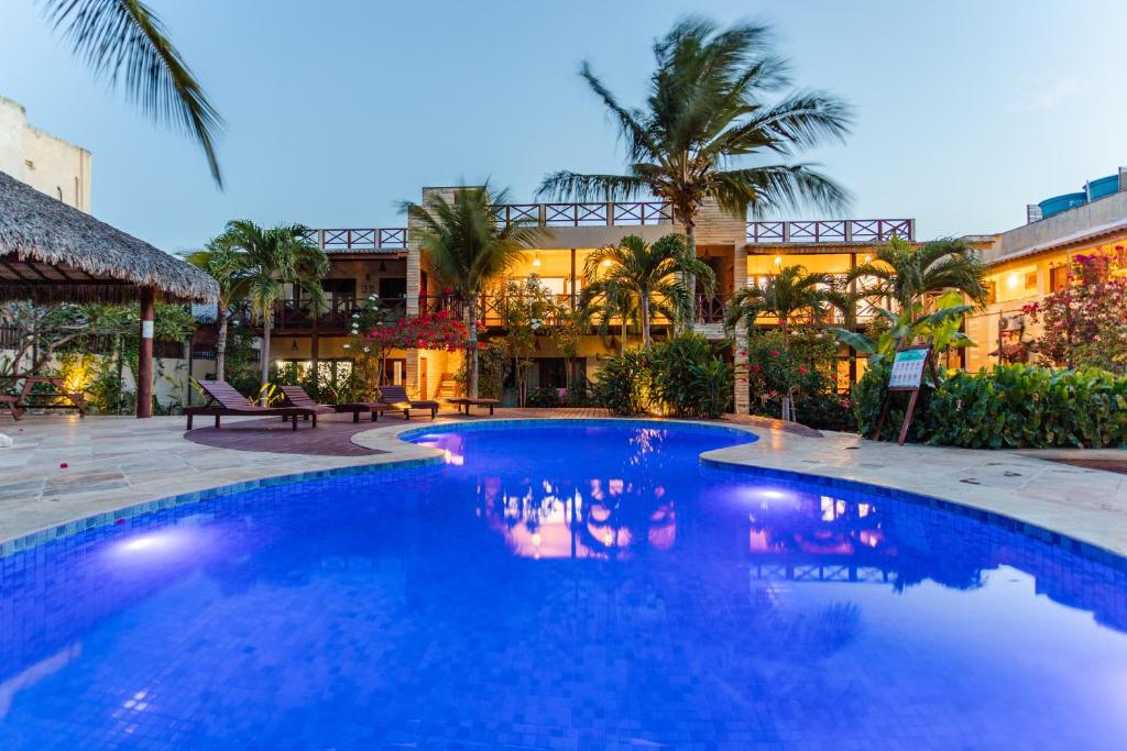 a large blue swimming pool in front of a building at Apartamento Breezes in Jericoacoara