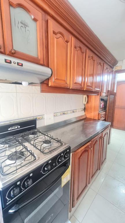 a kitchen with a stove and wooden cabinets at Acogedor y Residencial piso 3 in Cartagena de Indias