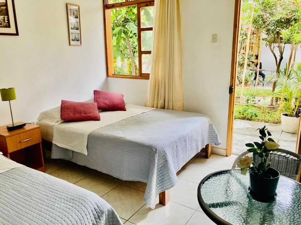 a bedroom with two beds and a glass table at Garden House Ica in Ica