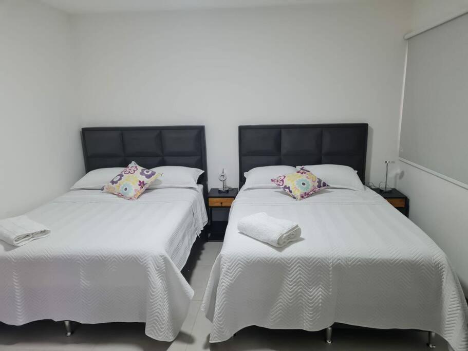 2 camas en una habitación con sábanas y almohadas blancas en Departamento Familiar en Equipetrol, en Santa Cruz de la Sierra