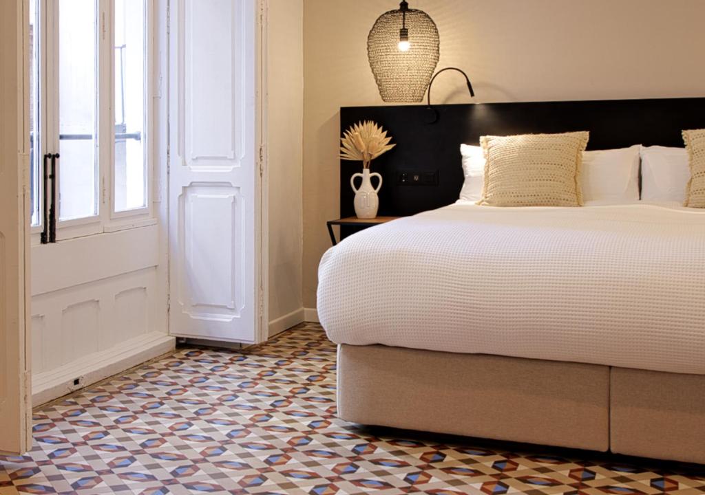 een slaapkamer met een groot bed en een raam bij VALOLA Boutique Rooms in Valencia