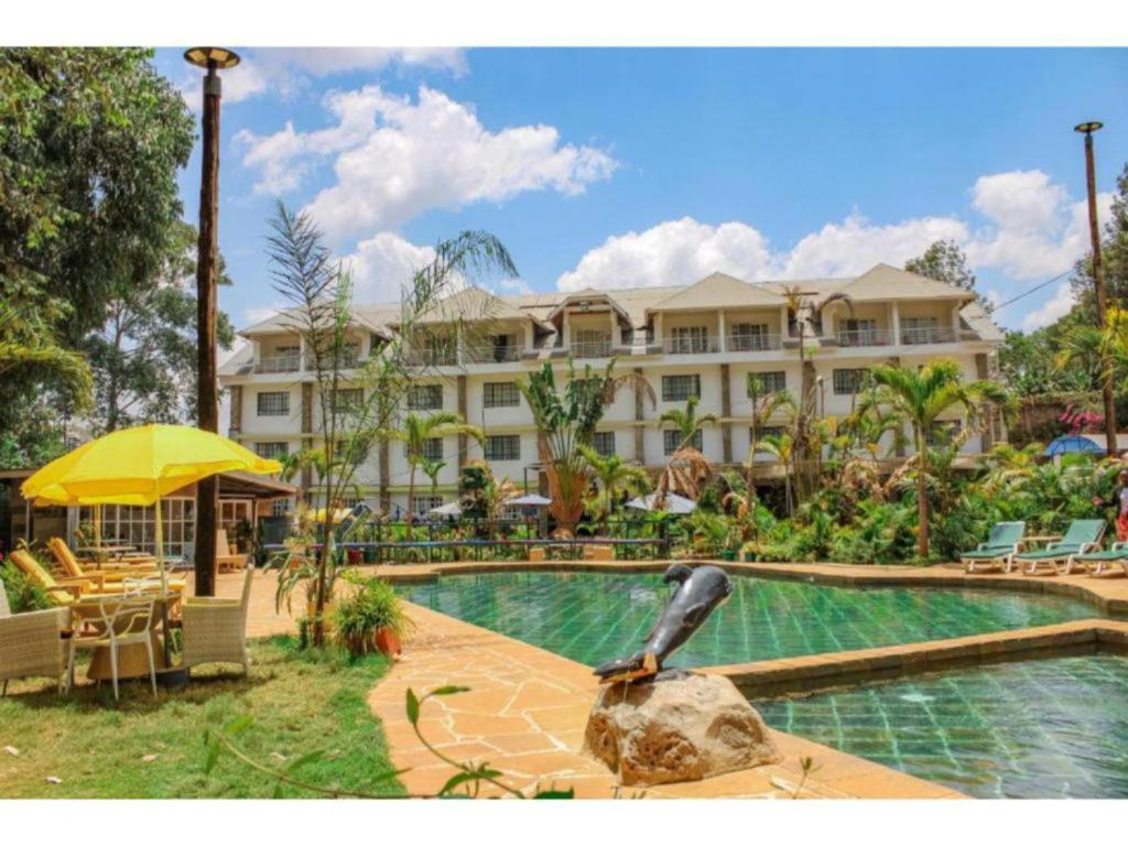 a resort with a pool and a bird statue in front of it at Tobriana in Nairobi