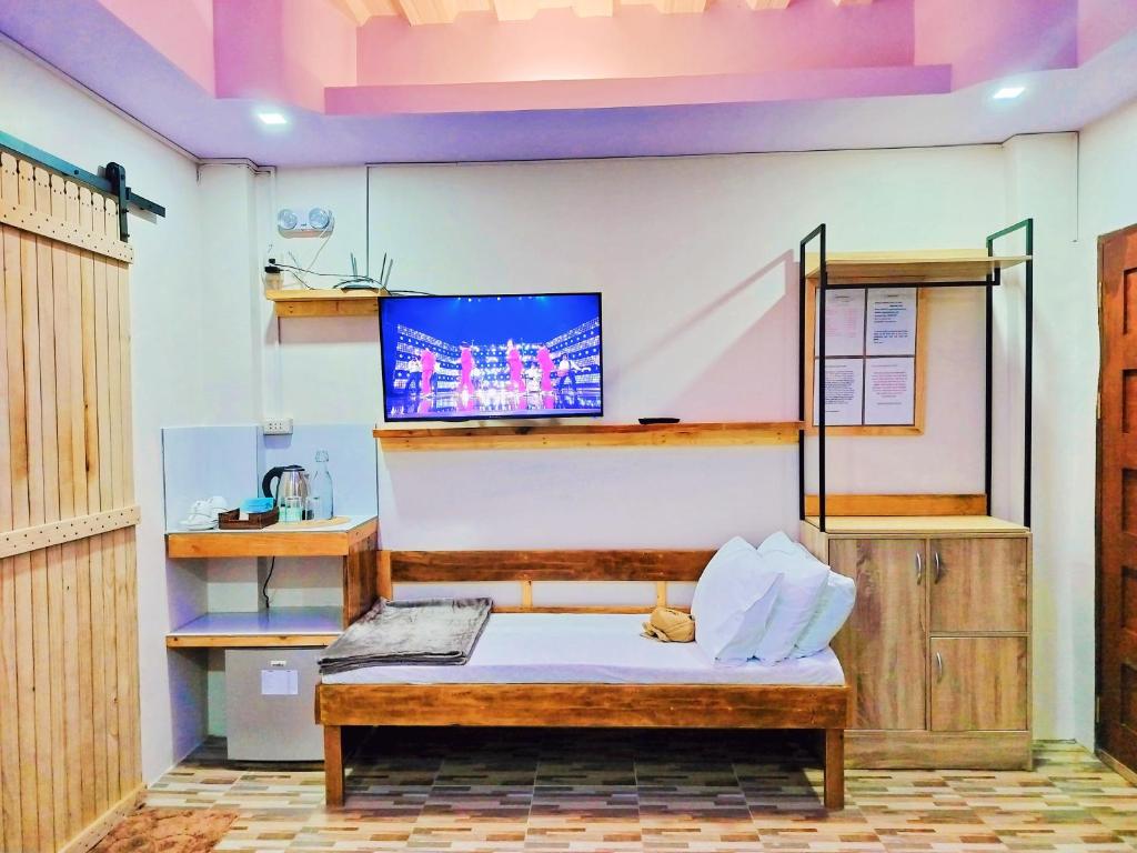Habitación con cama y TV en la pared. en Swakihan Guest House, en Siquijor