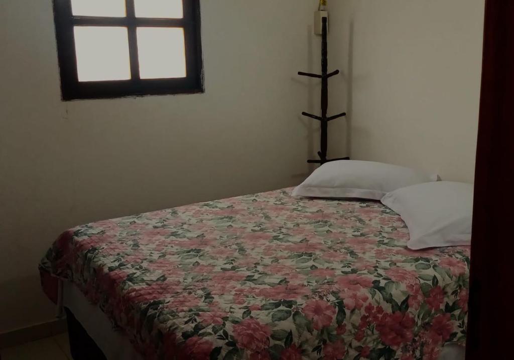 a bedroom with a bed with a floral bedspread and a window at Mangue em flor in Maxaranguape