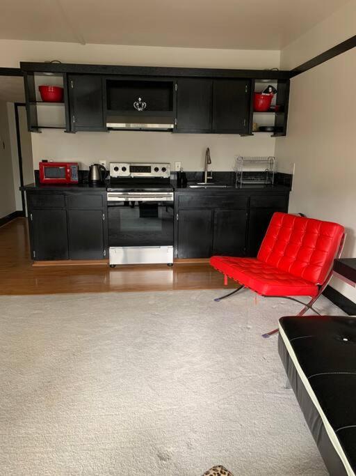 a living room with a red chair and a kitchen at Lucy's Place -STUDIO Apt with air-conditioning, Murphy bed in Hilo