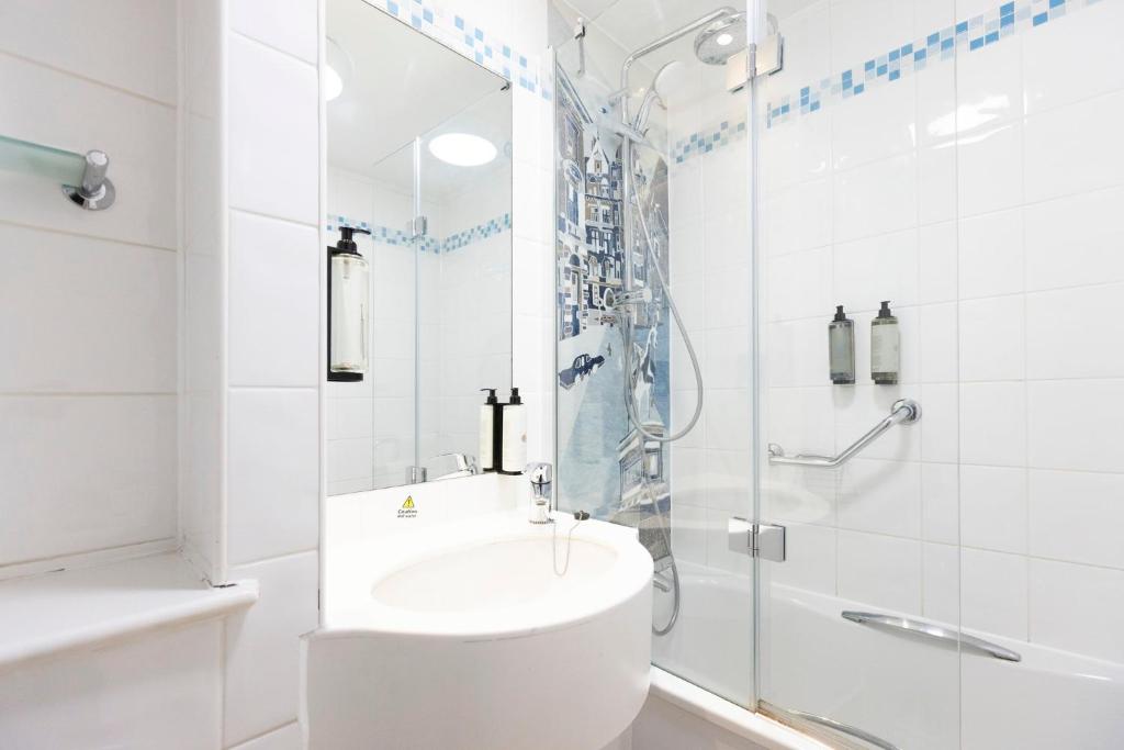 a white bathroom with a shower and a sink at Holiday Inn - Glasgow Airport by IHG in Paisley