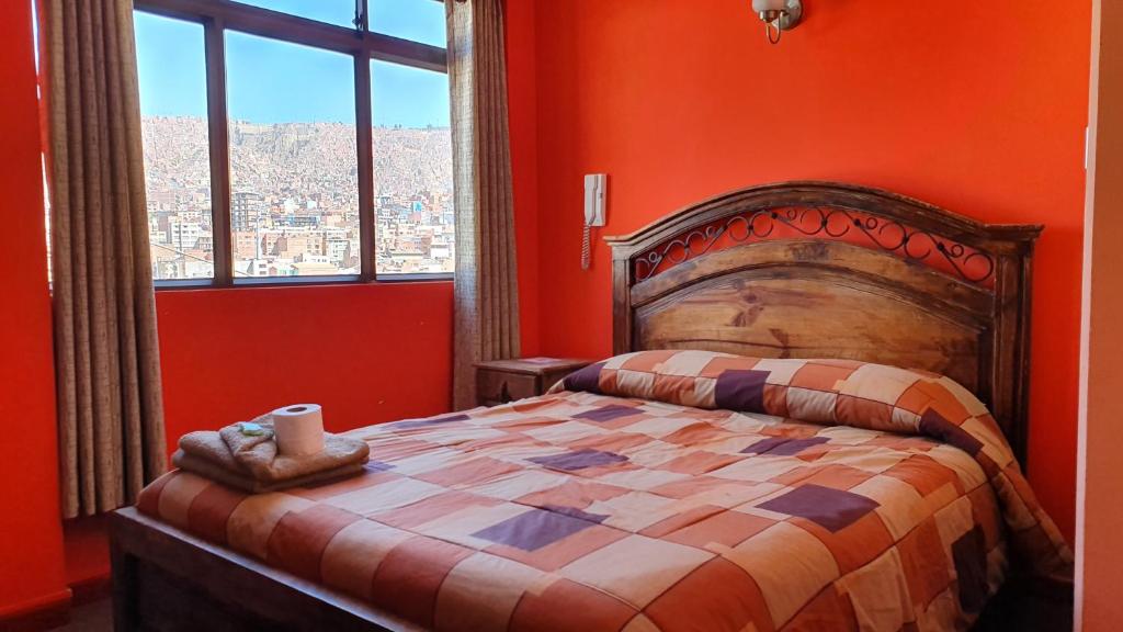 a bedroom with a bed with orange walls and a window at Bolivian Heights Hostel in La Paz