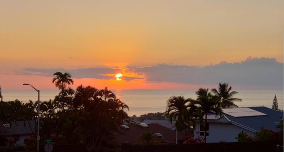 una puesta de sol sobre una ciudad con palmeras y casas en Komohana Hale LLC, en Kailua-Kona