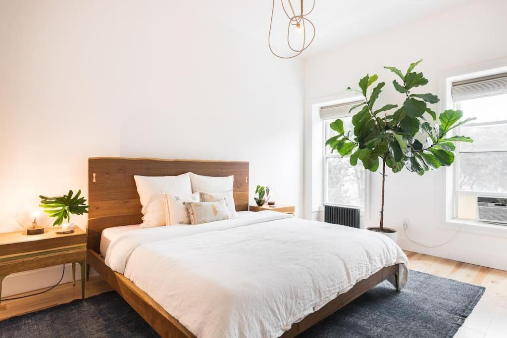 ブルックリンにあるAiry, modern Penthouse in a Brooklyn Brownstoneの大型ベッドと鉢植えの植物が備わるベッドルーム1室
