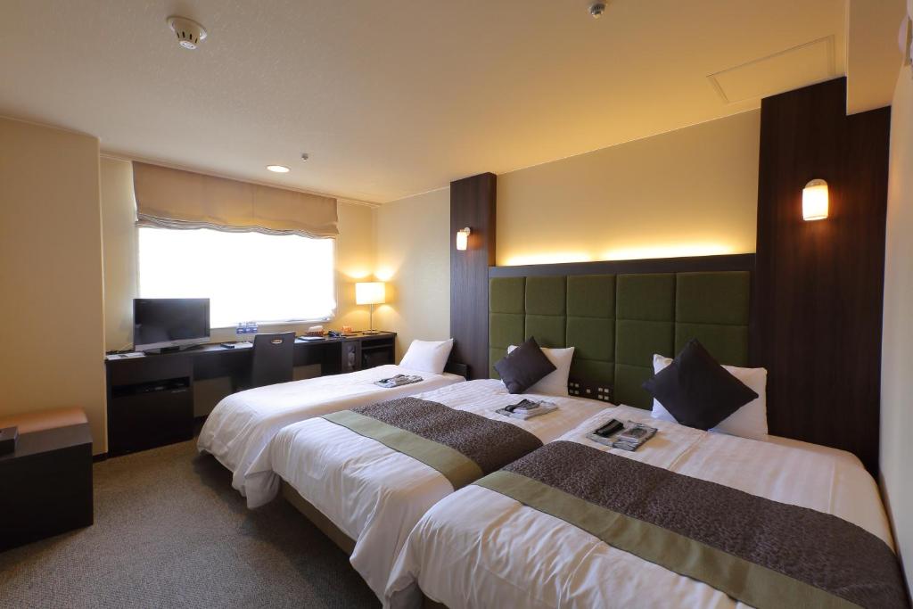 a hotel room with two beds and a desk at Hotel Binario Saga Arashiyama in Kyoto