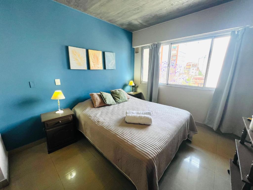 a blue bedroom with a bed and a window at Hermoso departamento barrio norte comodo amplio y luminoso in San Miguel de Tucumán