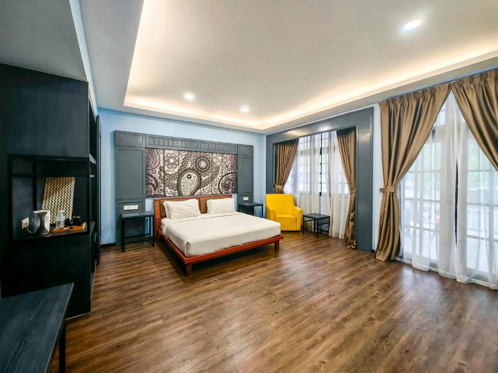 um quarto com uma cama e uma cadeira amarela em Cinta Sayang Resort em Sungai Petani
