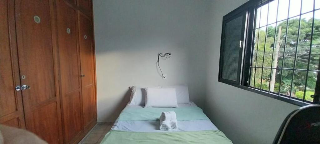 um pequeno quarto com uma cama e uma janela em Casa próxima ao centro! em Uberaba