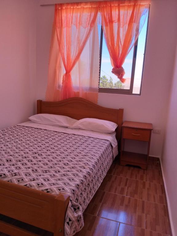 a bedroom with a bed and a window with curtains at Hostal Las Cruces in Arica