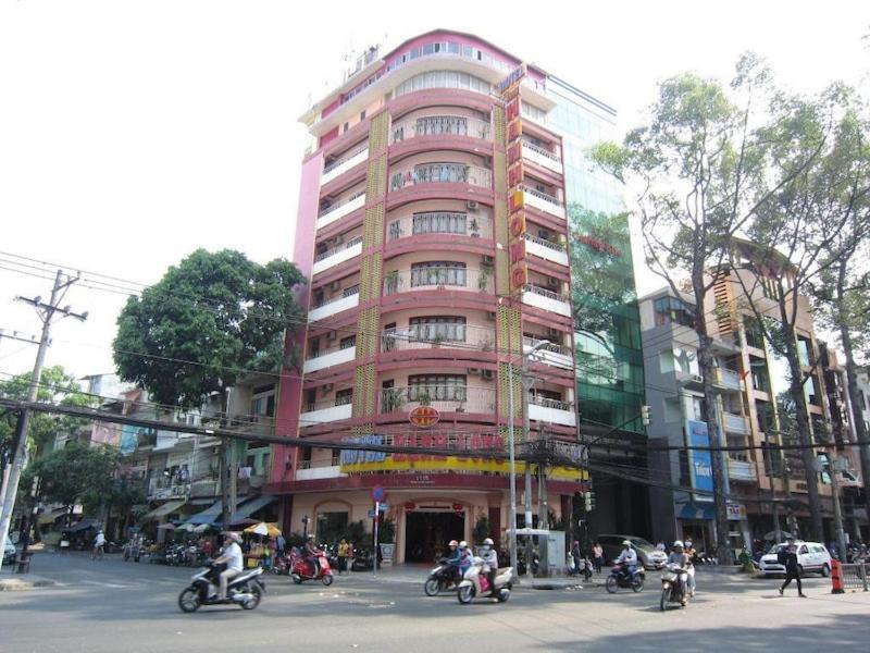 a large pink building with people riding motorcycles in front of it at Hạnh Long 2 - 1115 Trần Hưng Đạo, Quận 5 - by Bay Luxury Hotel in Ho Chi Minh City