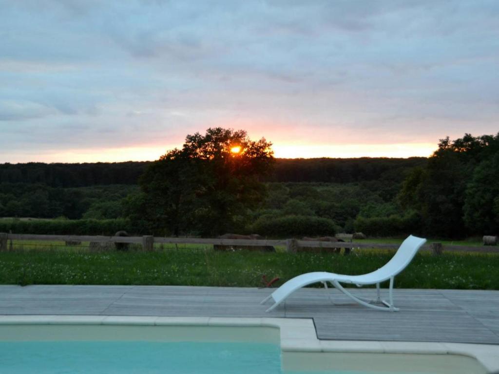 a white chair sitting on a patio at sunset at Gîte Le Brethon, 5 pièces, 8 personnes - FR-1-489-217 in Le Brethon