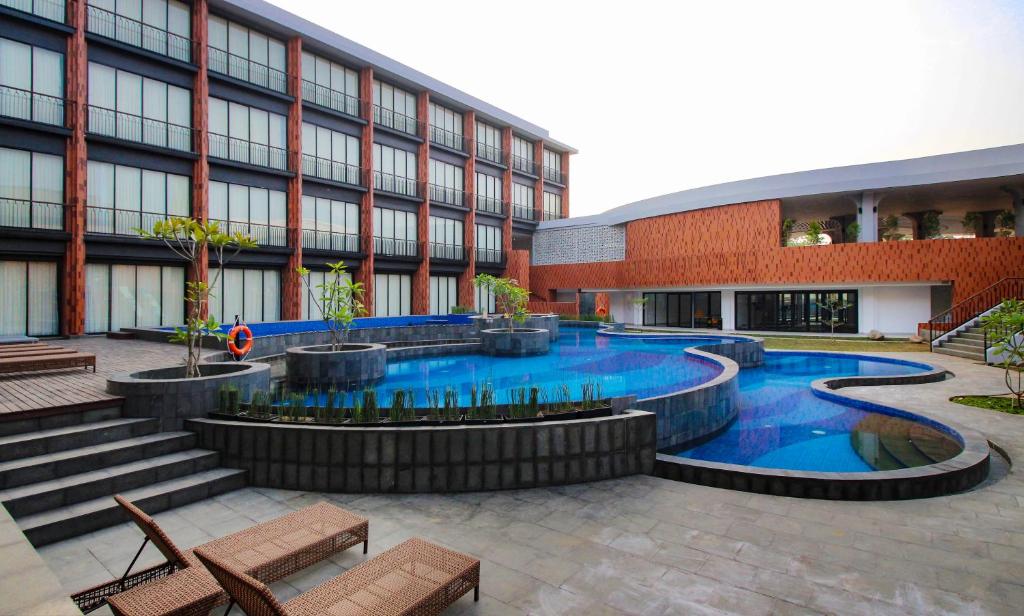 a building with a swimming pool in front of a building at Hotel Santika Premiere Linggarjati - Kuningan in Kuningan