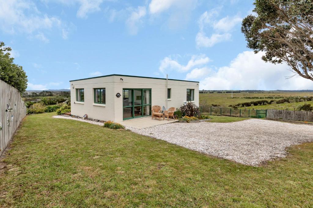 a small white house in the middle of a yard at The Mermaid's Rest - Whatuwhiwhi Holiday Home in Kaitaia