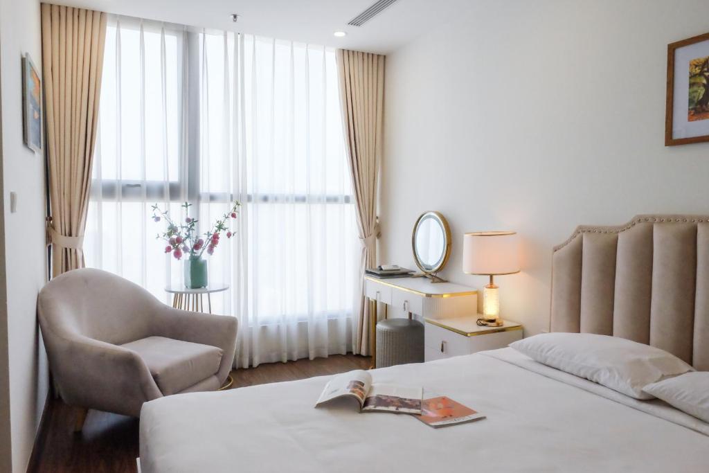 um quarto de hotel com uma cama e uma cadeira e uma janela em Aspaces Serviced Apartments - Vinhomes West Point em Hanói