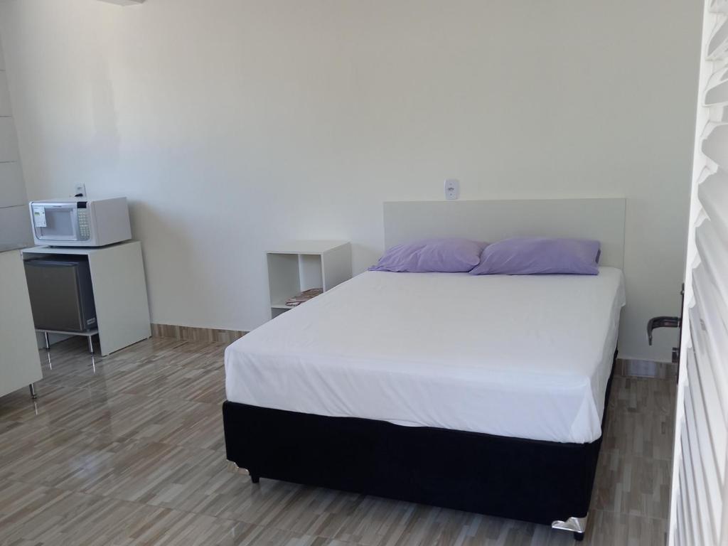 Apartamento Vila Telebrasilia في برازيليا: غرفة نوم بسرير ابيض وميكرويف
