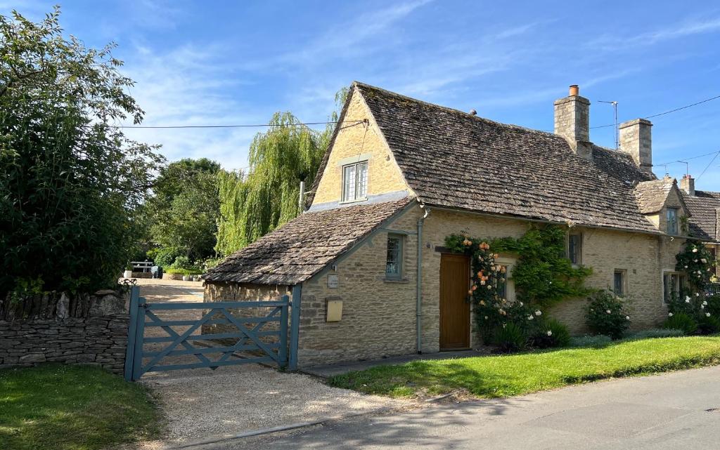 uma antiga casa de pedra com uma porta castanha em Culls Cottage, em Southrop