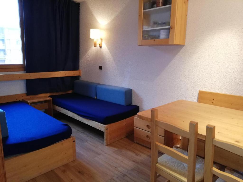 Zimmer mit einem Tisch und einem blauen Bett sowie einem Tisch und Stühlen in der Unterkunft Appartement Valmorel, 1 pièce, 4 personnes - FR-1-356-284 in Valmorel