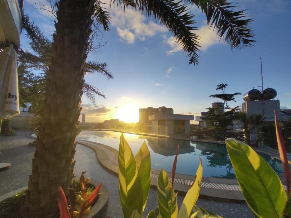 a view of a pool with a palm tree and the sunset at Babylon Mini Resort in Vung Tau