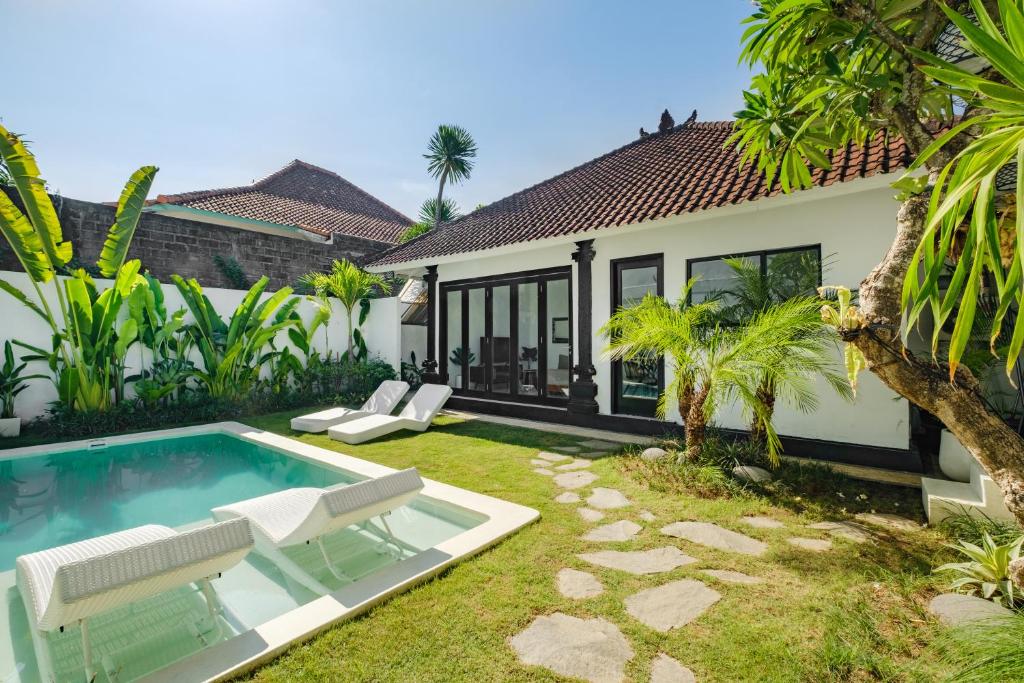 Un patio trasero con piscina y una casa. en Villa Marina Seminyak, en Seminyak