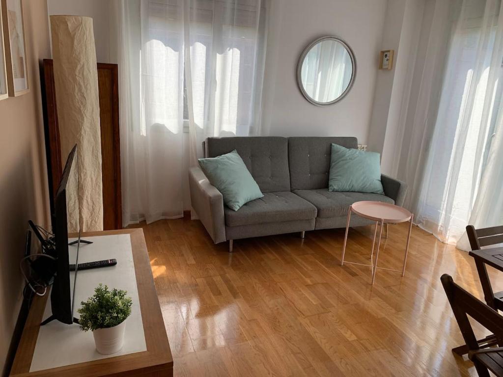 ein Wohnzimmer mit einem Sofa und einem Tisch in der Unterkunft Apartamento con jardín en Costa Quebrada in Liencres