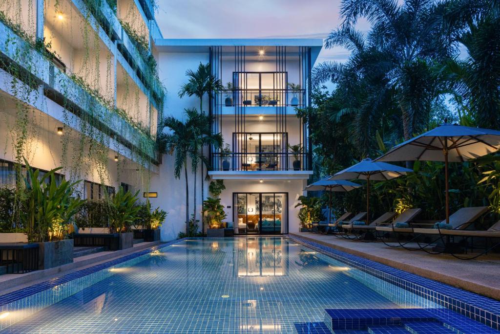 uma piscina num edifício com cadeiras e guarda-sóis em Grand Yard La Residence em Siem Reap