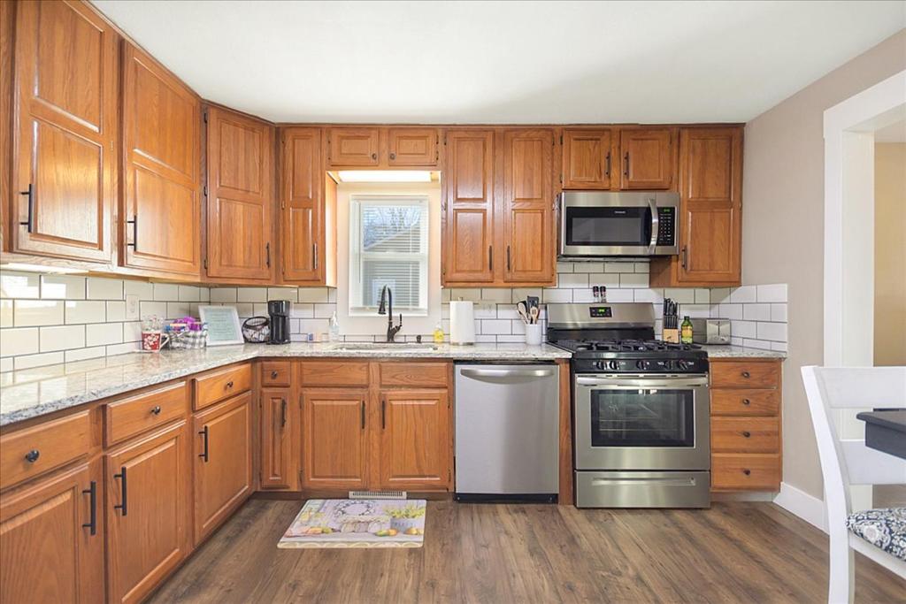 una cocina con armarios de madera y electrodomésticos de acero inoxidable en • Maverick House • Downtown Siloam Springs, en Siloam Springs