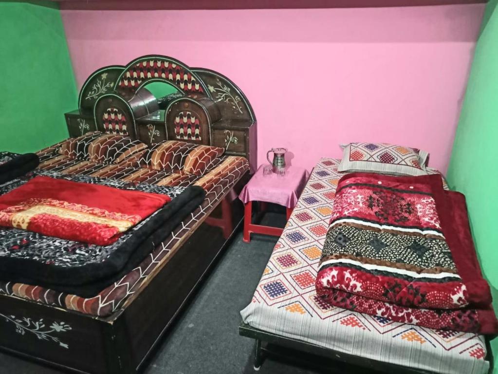 two beds are in a room with pink and green walls at Bajwal Home-Stay & Guest-House in Sari