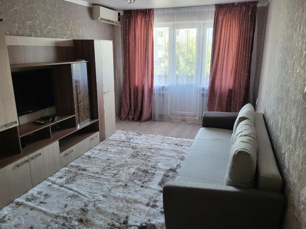 sala de estar con sofá y TV en 2-х комнатная квартира по ул. Муратбаева, en Kyzylorda