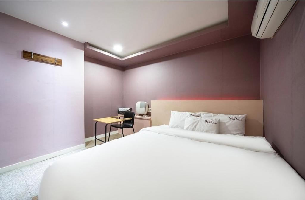 een slaapkamer met een wit bed en een tafel bij 9 to 9 motel in Gimhae