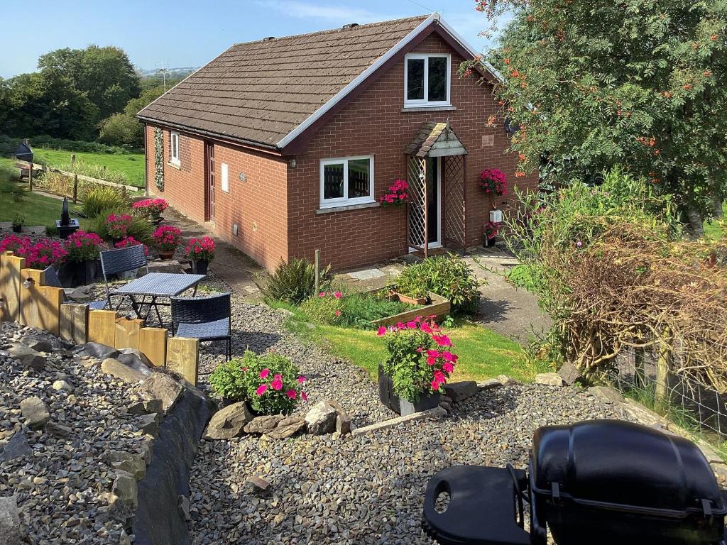 una pequeña casa con flores en un patio en Cartref Bach, en Llanwnen