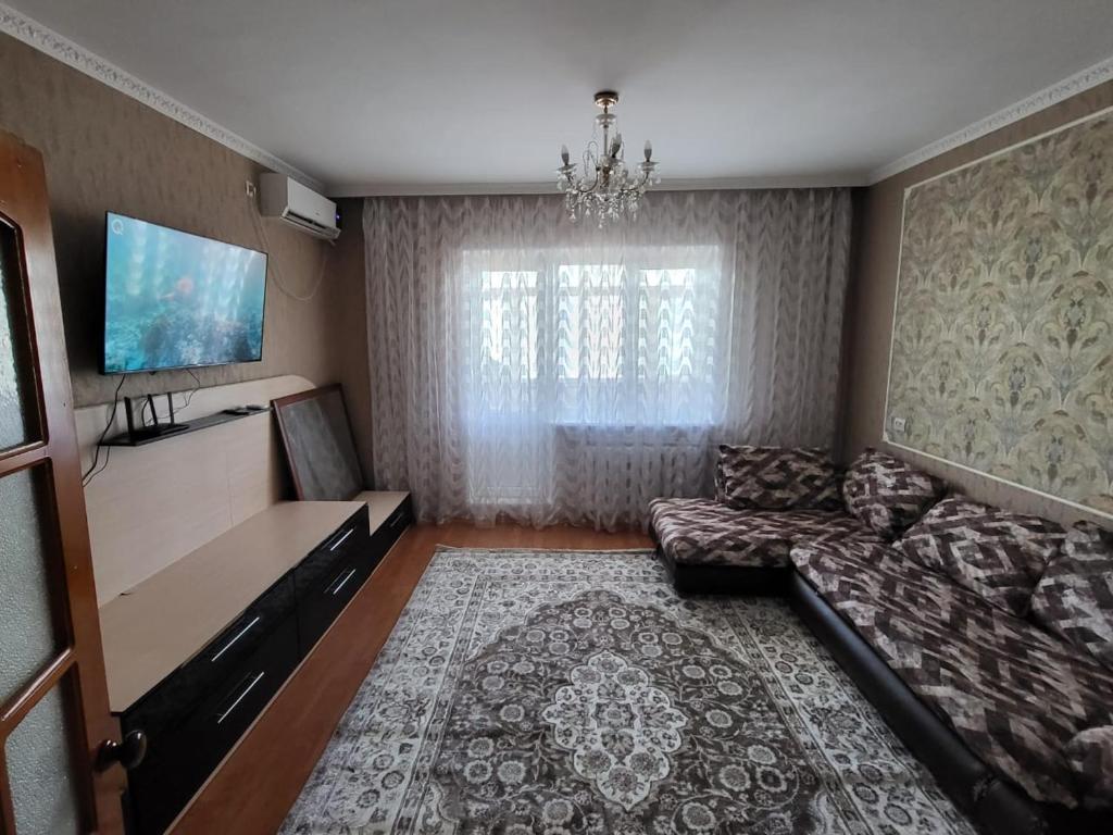 Il comprend un salon doté d'un canapé et d'une télévision à écran plat. dans l'établissement 3-х комнатная по ул. Есенова 19А, à Kyzylorda