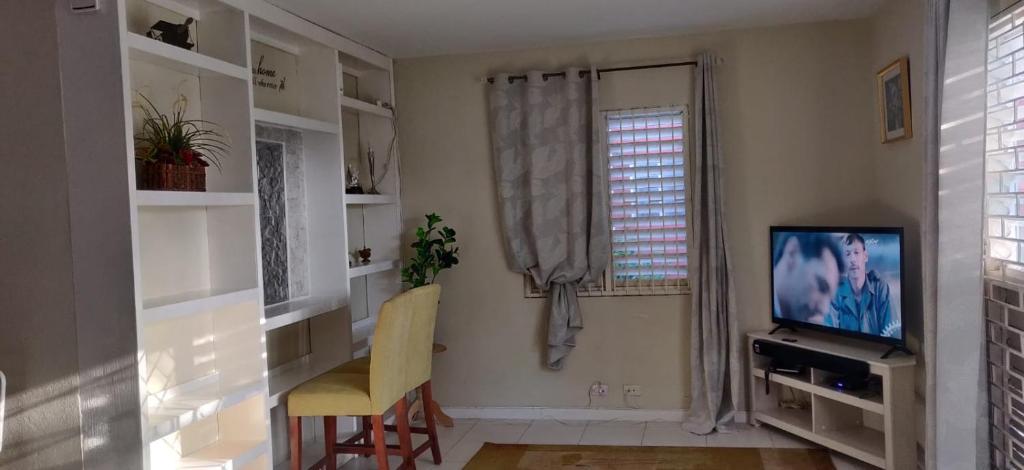 a living room with a tv and a window at Guango Grove Cozy Corner in Montego Bay