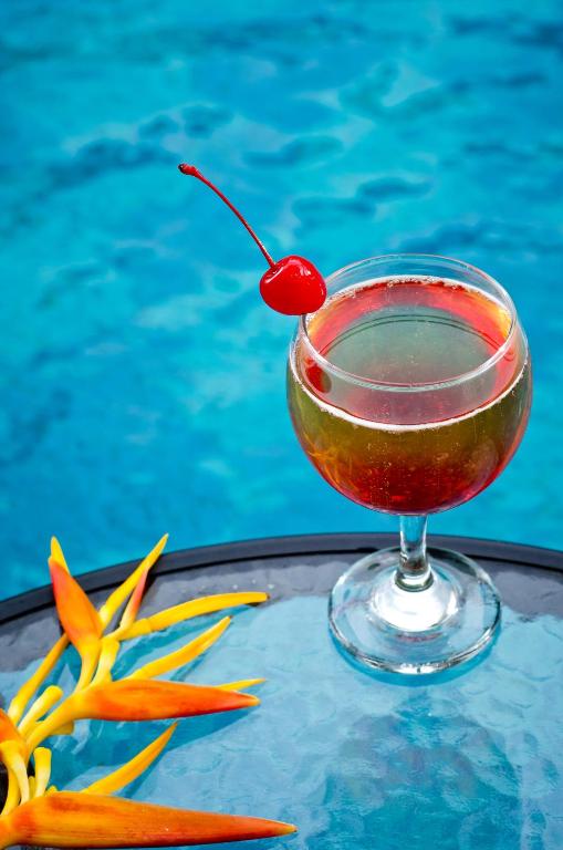 a drink with a cherry on a table next to a pool at Sri Phala Resort & Villa in Sanur