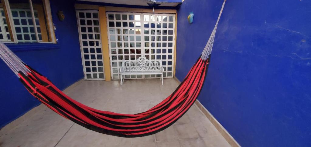 eine rote Hängematte in einem blauen Zimmer mit einer Bank in der Unterkunft House of Irma in Santa María Chimalhuacán