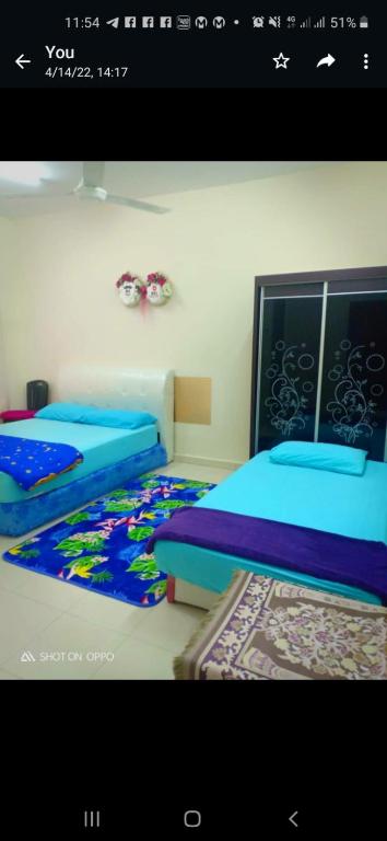two beds in a room with blue sheets at Homestay Rose Guest House 2.0 in Gambang