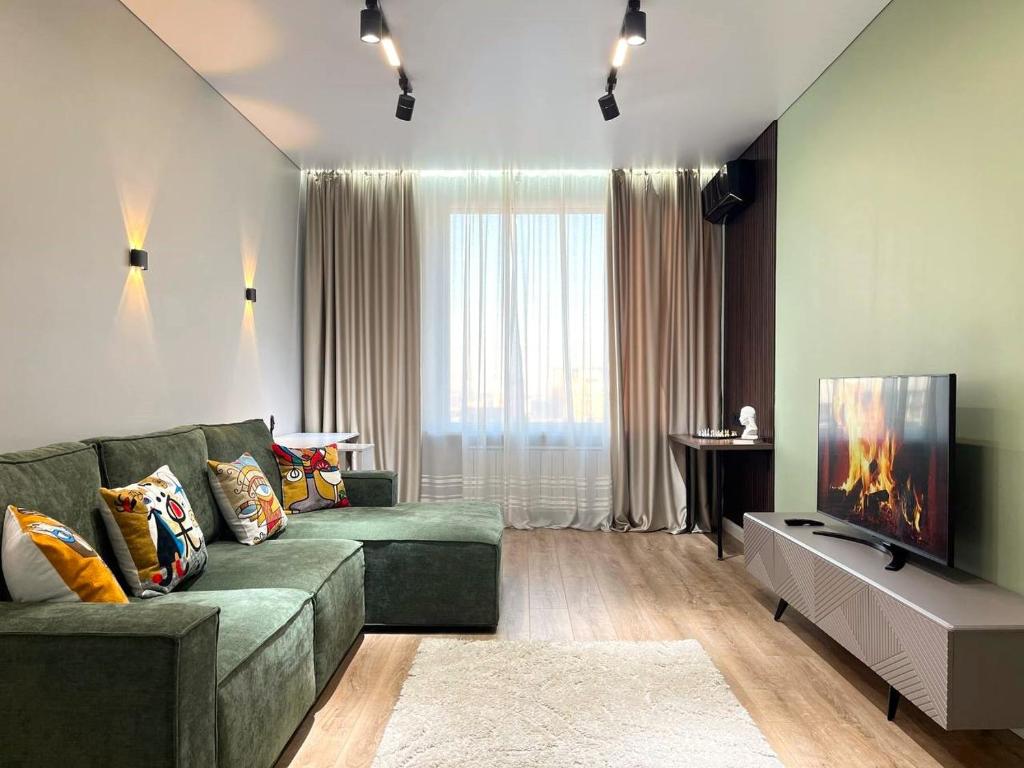 ein Wohnzimmer mit einem grünen Sofa und einem Flachbild-TV in der Unterkunft 3х-комнатная квартира бизнес класса in Almaty