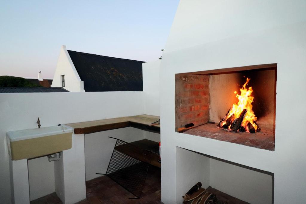 a fireplace in a room with a sink and a fire at Owlet Cottage In Arniston in Arniston