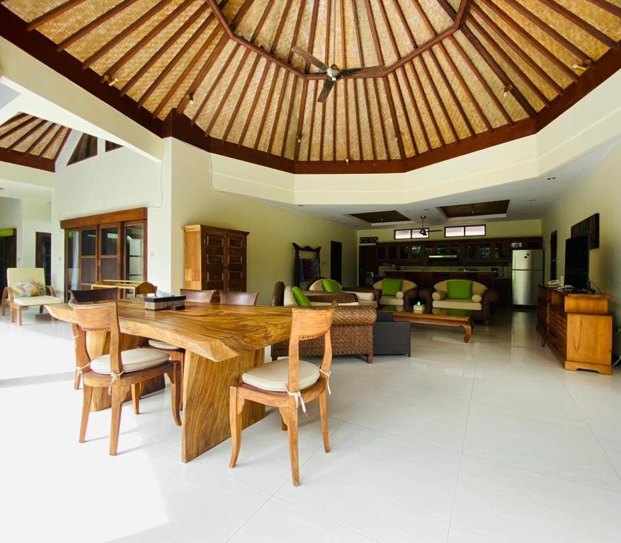 uma ampla sala de estar com uma mesa de madeira e cadeiras em Bali Jade Villas em Sanur