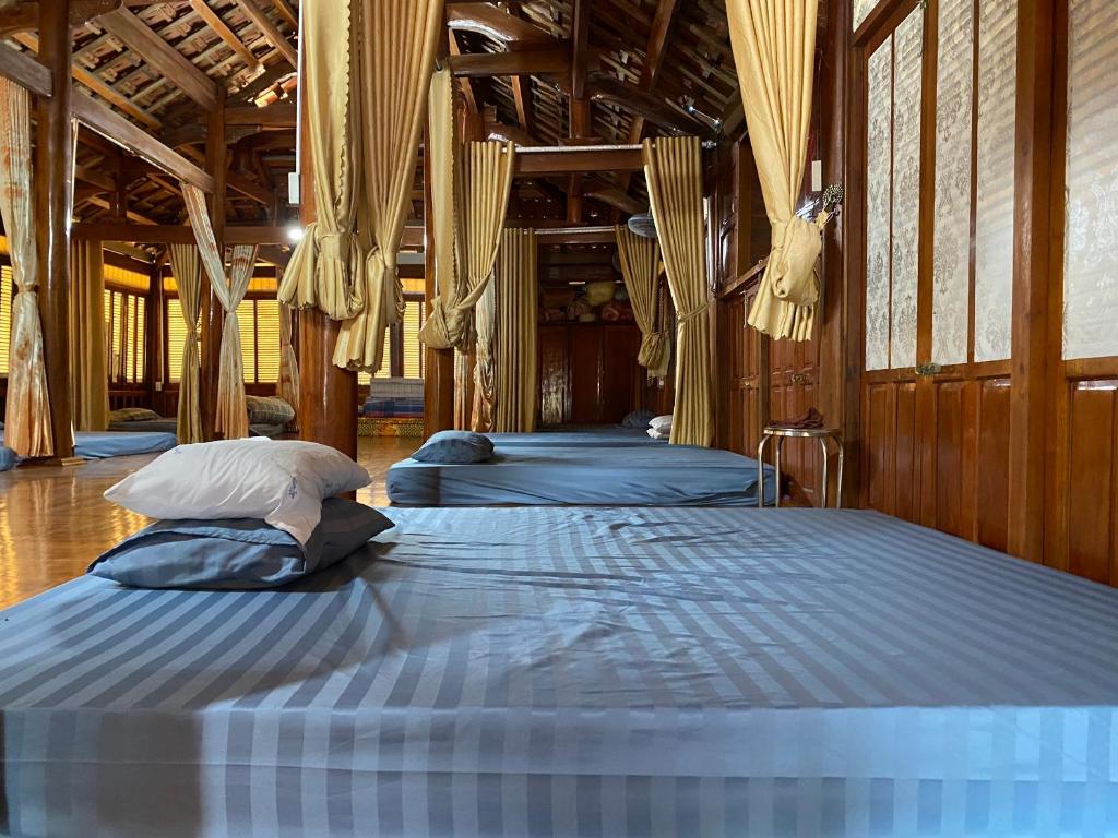 um quarto com 3 camas num quarto com janelas em Homestay-Nhà Sàn Ngán Chải em Ha Giang