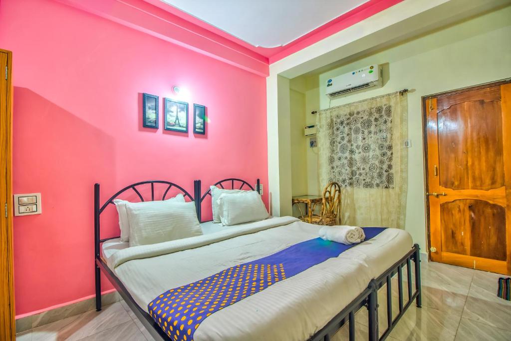 a bedroom with a pink wall with a bed at Downtown in Calangute