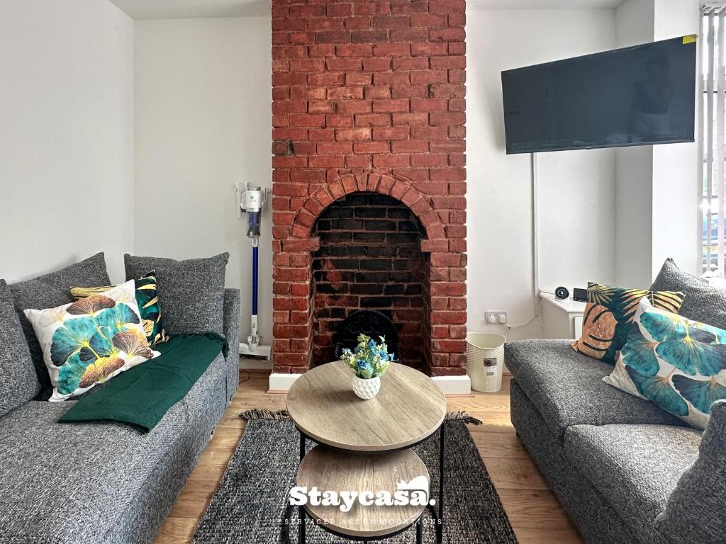 a living room with two couches and a brick fireplace at Stunning 3bdr 2ba House With Free Street Parkin in Birmingham
