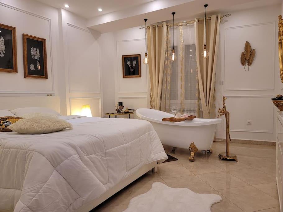 a white bedroom with a bed and a bath tub at Dar Nadia in 'Aïn Benian